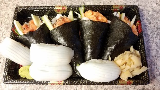 spicy tuna and salmon handroll and squid sushi in container on counter