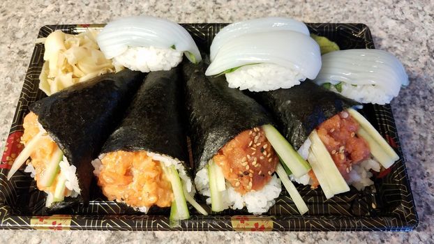 spicy tuna and salmon handroll and squid sushi in container on counter