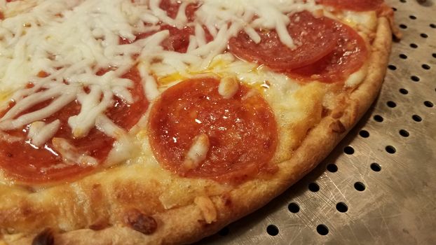 pepperoni pizza with cheese and grease on metal baking tray