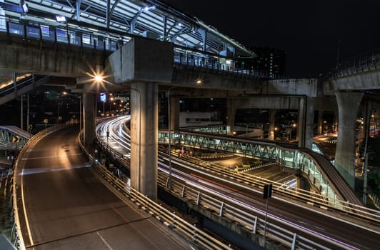 Overpass of the light trails with Bangkok city background at night. Beautiful curves. Selective focus.