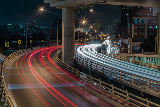 Overpass of the light trails with Bangkok city background at night. Beautiful curves. Selective focus.
