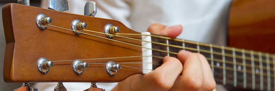 Young boy playing guitar. Close-up of man hand playing classic guitar. teenager learning playing guitar, Banner or panoramic shot.
