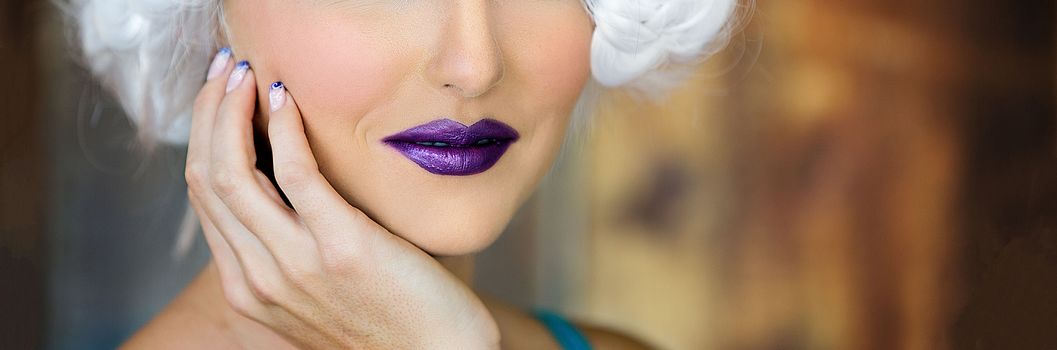 Close up of the lower face of a beautiful young woman wearing purple lipstick