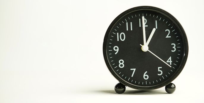 Decorative close-up black analog alarm clock for 13 o'clock separating white background with copy space.