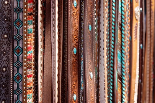 A group of women's country style leather belts for sale at a market stall
