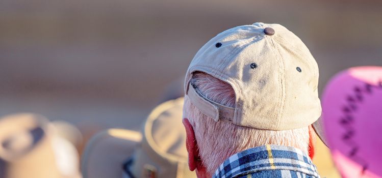 A senior caucasian retired male wearing a grey cap to keep off the sun on a hot summer day, blurred background
