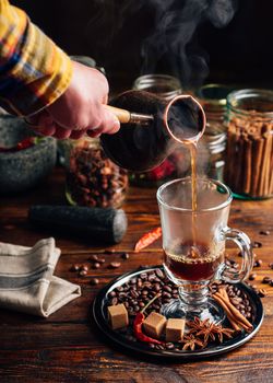 Man Pour Hot Soaring Coffee in Glass. Different Spices and Coffee Grains on Metal Tray.