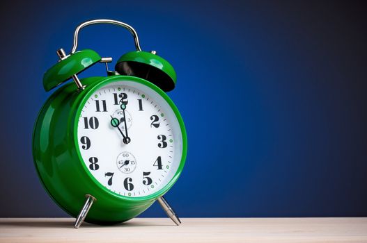 Retro big green alarm clock on blue background