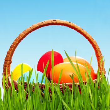 Wicker basket with easter eggs in green grass