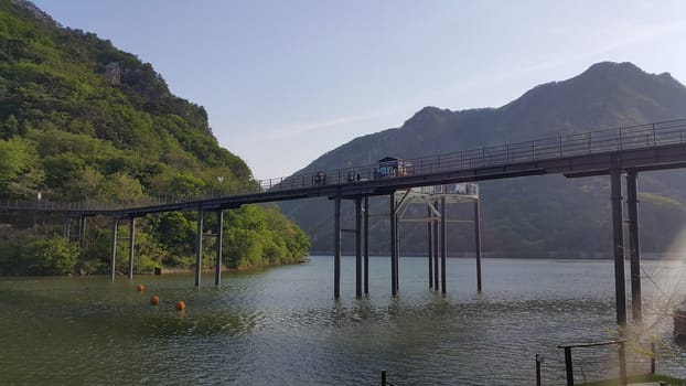View of beautiful scene of river water and green trees on large hills on a sunny day with blue sky in background. A lovely landscape with breathtaking view over the horizon .