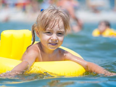 Portrait of little smiling girl with inflatable rubber circle in the sea in sunny day. Summer vacations concept.