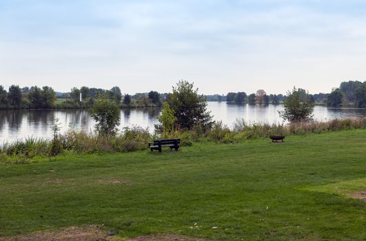 the river maas in holland with bench and fireplace at the border of the water, the maas is a river for watersport but also for water transport