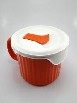 Orange heavy duty mug with handle and ridges use to pour liquid content and soup