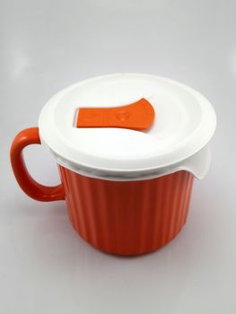 Orange heavy duty mug with handle and ridges use to pour liquid content and soup