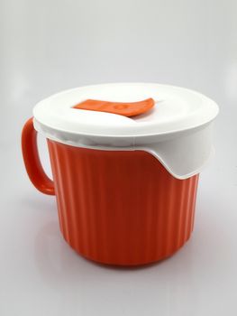 Orange heavy duty mug with handle and ridges use to pour liquid content and soup