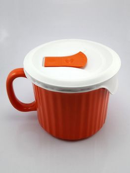 Orange heavy duty mug with handle and ridges use to pour liquid content and soup