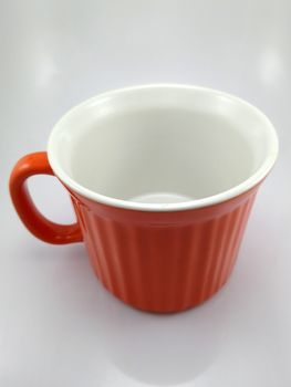 Orange heavy duty mug with handle and ridges use to pour liquid content and soup