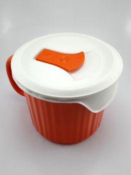 Orange heavy duty mug with handle and ridges use to pour liquid content and soup