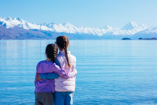 Young children look over Mt Cook and Lake Pukaki on a crystal clear spring morning in New Zealand