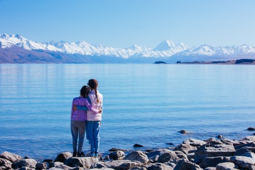 Young children look over Mt Cook and Lake Pukaki on a crystal clear spring morning in New Zealand
