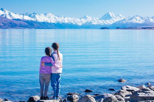 Young children look over Mt Cook and Lake Pukaki on a crystal clear spring morning in New Zealand