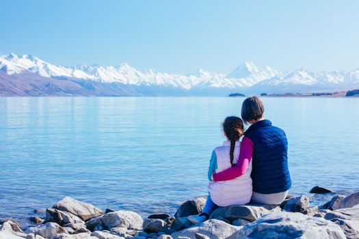 A young child and her Mum look over Mt Cook and Lake Pukaki on a crystal clear spring morning in New Zealand