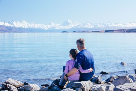A young child and her Dad look over Mt Cook and Lake Pukaki on a crystal clear spring morning in New Zealand
