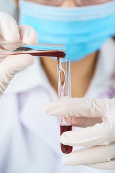 Technician scientist analyzing holding blood sample in test tube in laboratory for testing it on COVID, COVID-19, coronavirus virus analysis