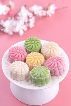 Colorful snow skin moon cake, sweet snowy mooncake, traditional savory dessert for Mid-Autumn Festival on pastel pale pink background, close up, lifestyle.