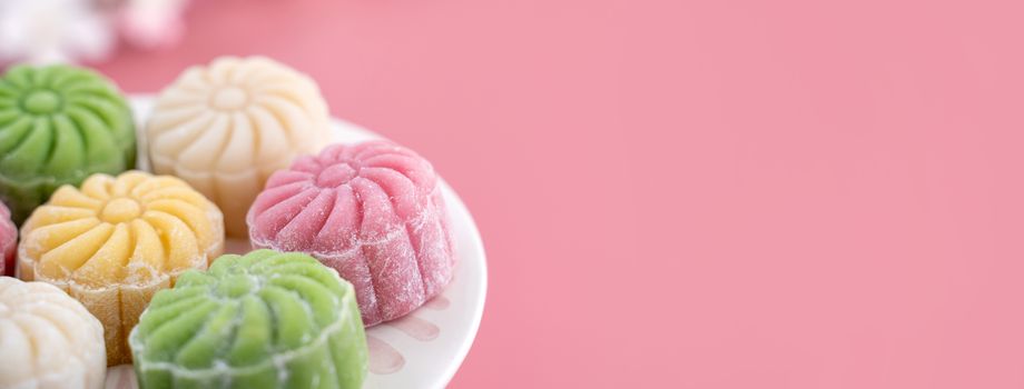 Colorful snow skin moon cake, sweet snowy mooncake, traditional savory dessert for Mid-Autumn Festival on pastel pale pink background, close up, lifestyle.