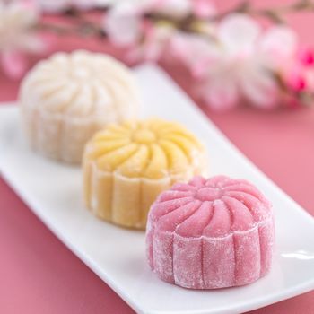 Colorful snow skin moon cake, sweet snowy mooncake, traditional savory dessert for Mid-Autumn Festival on pastel pale pink background, close up, lifestyle.