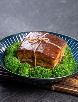 Dong Po Rou (Dongpo pork meat) in a beautiful plate with green broccoli vegetable, traditional festive food for Chinese new year cuisine meal, close up.