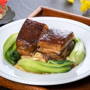 Dong Po Rou (Dongpo pork meat) in a beautiful plate with green broccoli vegetable, traditional festive food for Chinese new year cuisine meal, close up.