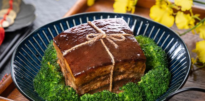 Dong Po Rou (Dongpo pork meat) in a beautiful plate with green broccoli vegetable, traditional festive food for Chinese new year cuisine meal, close up.