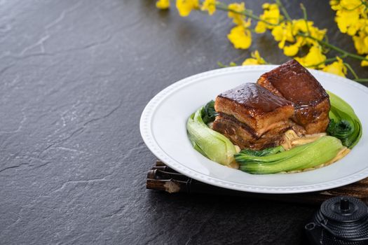 Dong Po Rou (Dongpo pork meat) in a beautiful plate with green broccoli vegetable, traditional festive food for Chinese new year cuisine meal, close up.