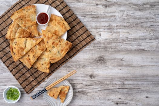 Taiwanese food - delicious flaky scallion pie pancakes on bright wooden table background, traditional snack in Taiwan, top view.