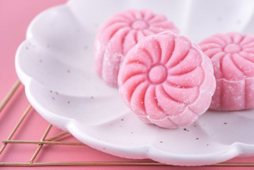 Colorful snow skin moon cake, sweet snowy mooncake, traditional savory dessert for Mid-Autumn Festival on pastel pale pink background, close up, lifestyle.