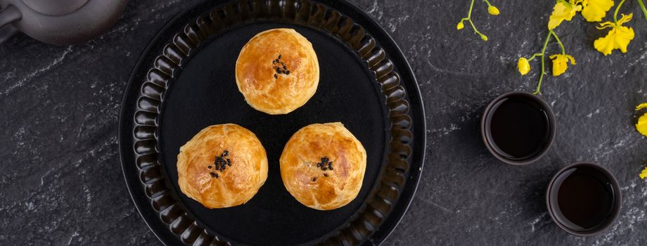 Moon cake yolk pastry, mooncake for Mid-Autumn Festival holiday, top view design concept on dark wooden table with copy space, flat lay, overhead shot