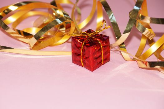 shiny red gift box and gold ribbon on pink background, copy space