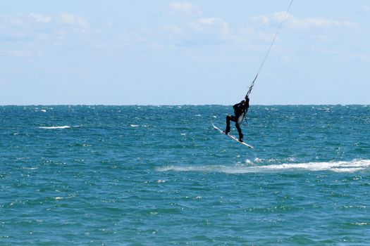 a man jumps on a kiteboard over the sea.