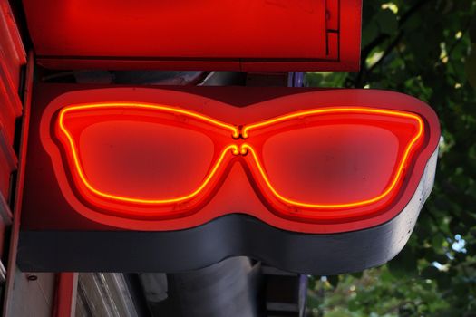 outdoor illuminated advertising sign in the shape of red glasses close up