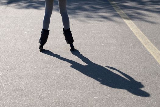 a shadow on the asphalt from a roller-skating girl.