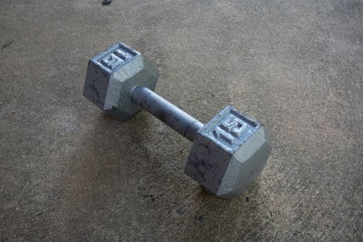 An Old Silver Fifteen Pound Weight on Concrete