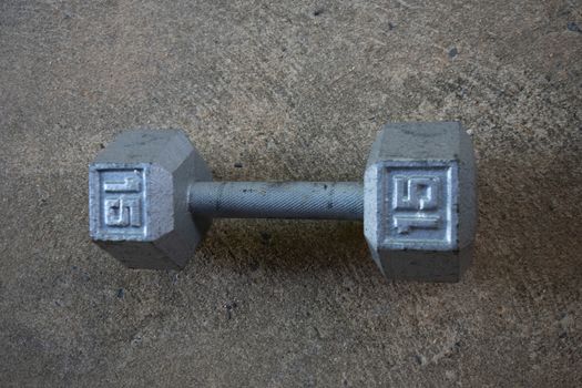 An Old Silver Fifteen Pound Weight on Concrete