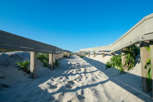 A Sandy Beach Path With a Wooden Fence on Each Side Casting Shadows in Wildwood New Jersey