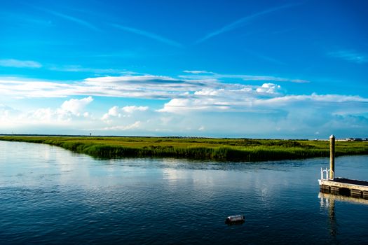 A View of the Lush Bay at Wildwood New Jersey With a Small Dock and a Floating Bouey in the Foreground and a Bridge in the Background