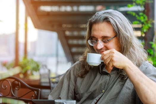 Men sitting in the at drinking coffee and using laptop a home porch