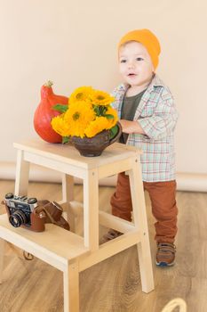.The little boy stands in the autumn photo zone in the studio and smiles.