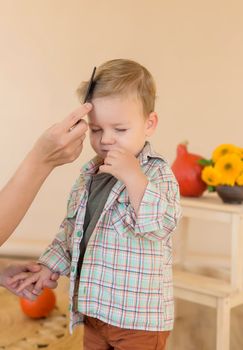 Mom combing her little son in the studio before a photo session