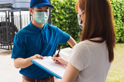 Asian young delivery man courier shopping online with package post box in uniform protective face mask coronavirus he making service woman customer using pen signature on paper book at home, COVID-19